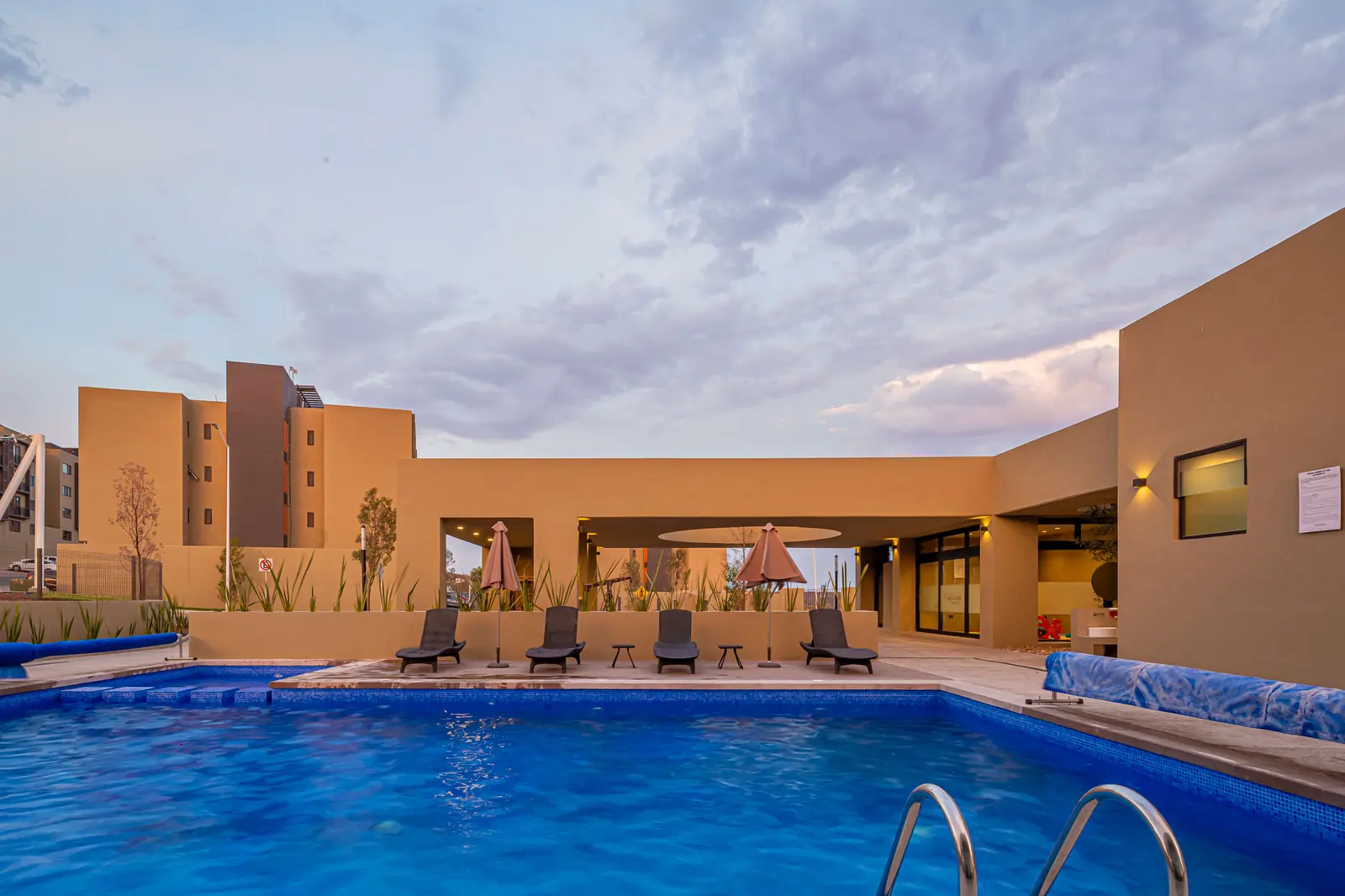 Alberca y casa club de Villas del Refugio Nogales al atardecer, departamentos nuevos en El Refugio, Querétaro